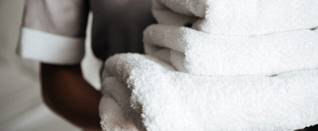 Close up of a young hotel maid holding clean folded towels